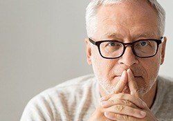 Older man with glasses contemplating
