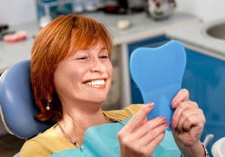 Older woman admiring her smile in hand mirror