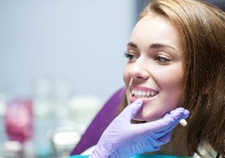 Dentist inspecting woman’s smile after cosmetic procedure