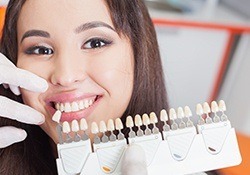 Woman's smile compared with tooth color chart