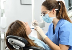 A dental hygienist cleaning a female patient’s teeth