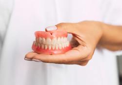 Woman holding full dentures