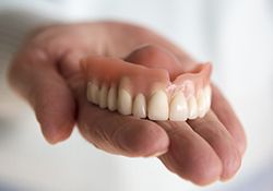 Hand holding a full denture