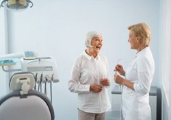 a patient smiling at her dentist and discussing dentures