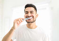 Man preventing dental emergencies in New Lenox by brushing
