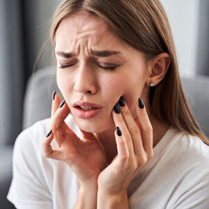 a woman rubbing her cheeks from pain