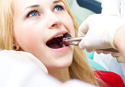 a dentist grabbing onto a dental patients infected tooth with tools