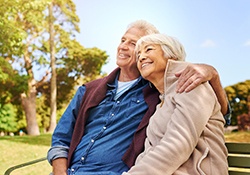 Older couple with dental implants in New Lenox sitting on bench