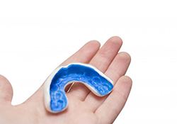 person holding a blue mouthguard in their hand