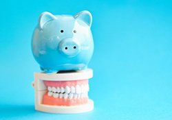 light blue piggy bank sitting on top of a set of false teeth