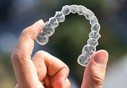 Person holding Invisalign aligner in New Lenox