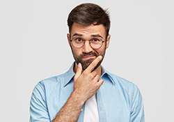 Man with glasses with hand on chin looking curious