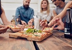 Group of friends eating pizza around table