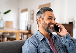 Man smiling while talking on phone at home