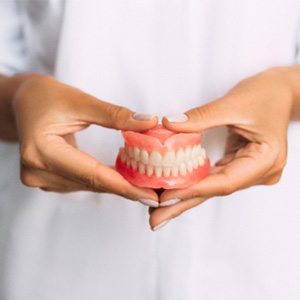 A dentist holding dentures in his hands