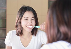 woman brushing her teeth to prevent dental emergencies in New Lenox