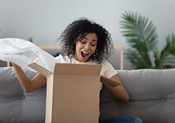 woman excitedly opening a cardboard box 