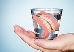 Full set of dentures in glass of water