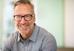 Man with glasses smiling after root canal therapy in New Lenox, IL