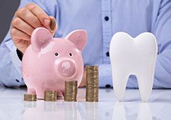Piggy bank, coins, and tooth representing cost of root canal therapy in New Lenox, IL