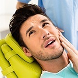 Man in dental chair holding jaw