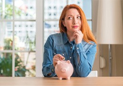 woman and piggy bank for cost of teeth whitening New Lenox