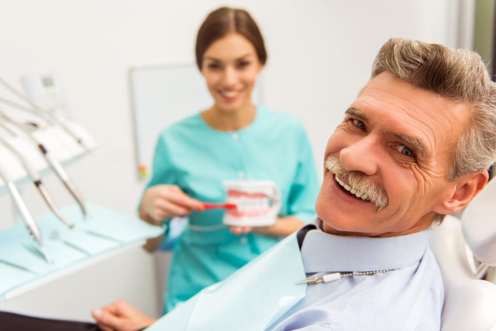 Dentist showing patient how to care for dentures