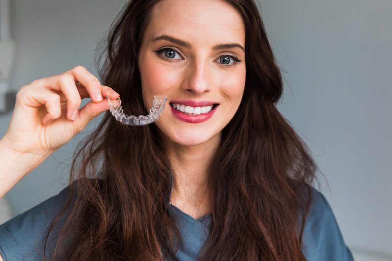 a woman holding Invisalign aligners in New Lenox