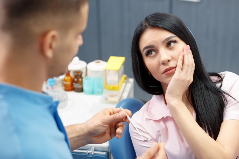 Patient holding their cheek at an emergency dental appointment