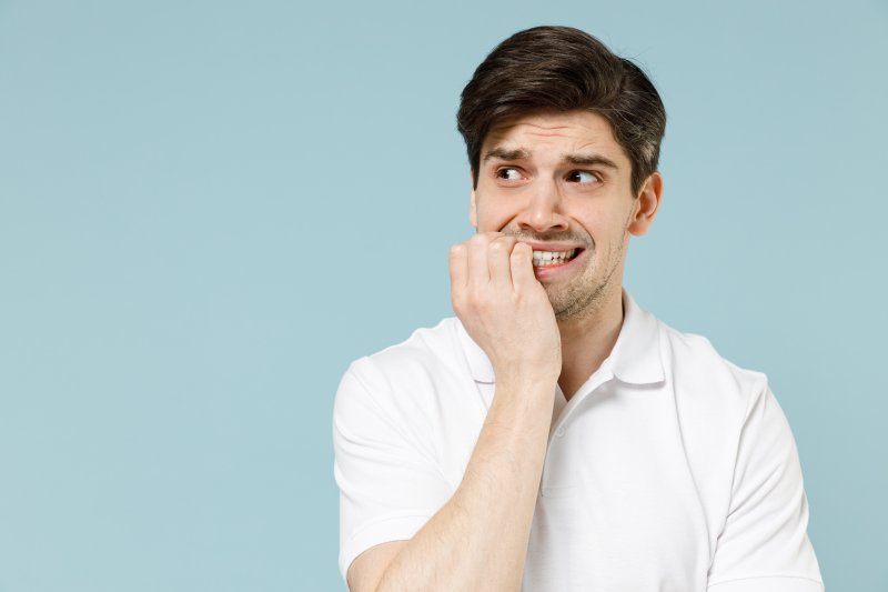 A nervous man looking to the side while biting his fingernails