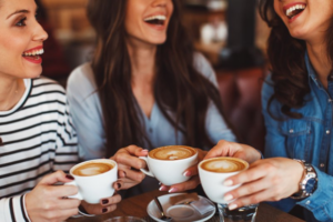Three friends chatting while holding their lattes 