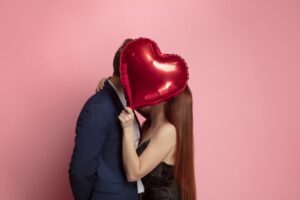 Couple kissing behind a heart balloon