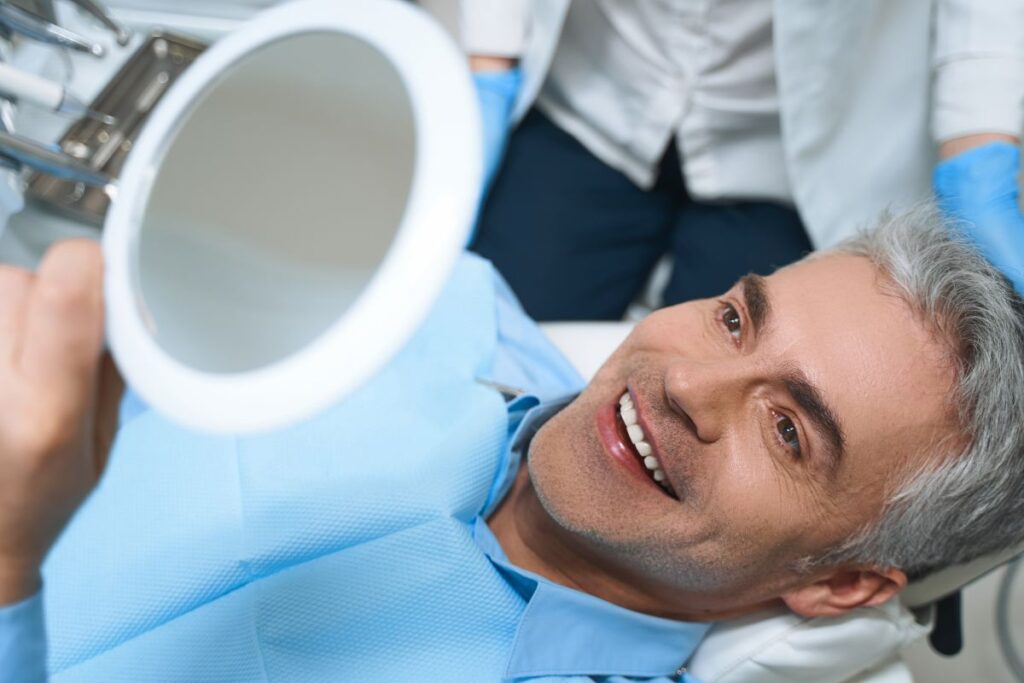 A man looking in a mirror at his new dental implants