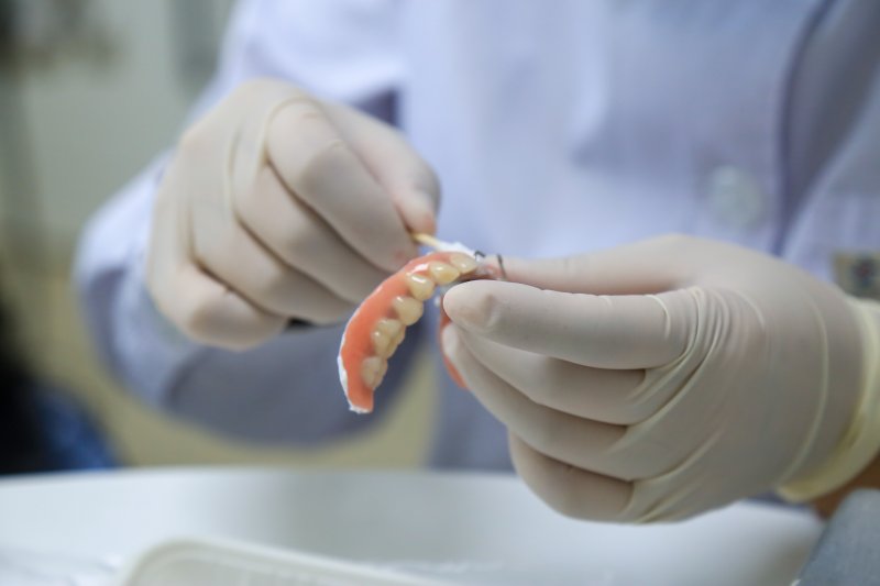 A dental professional repairing a removable denture