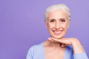 Older woman smiling with confidence with hand held flat under chin.